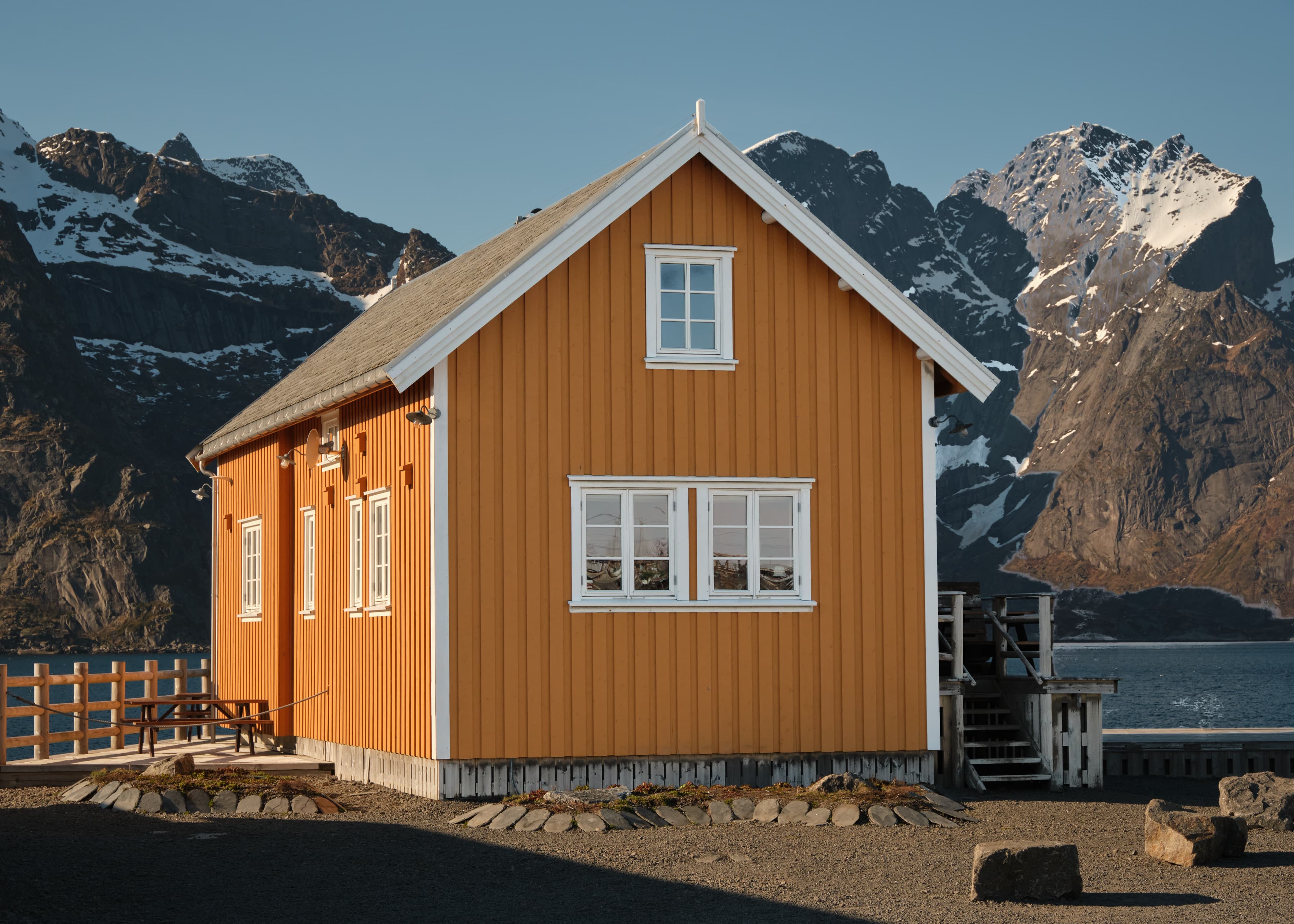 Classic orange rorbu cabin, snow-capped peaks behind