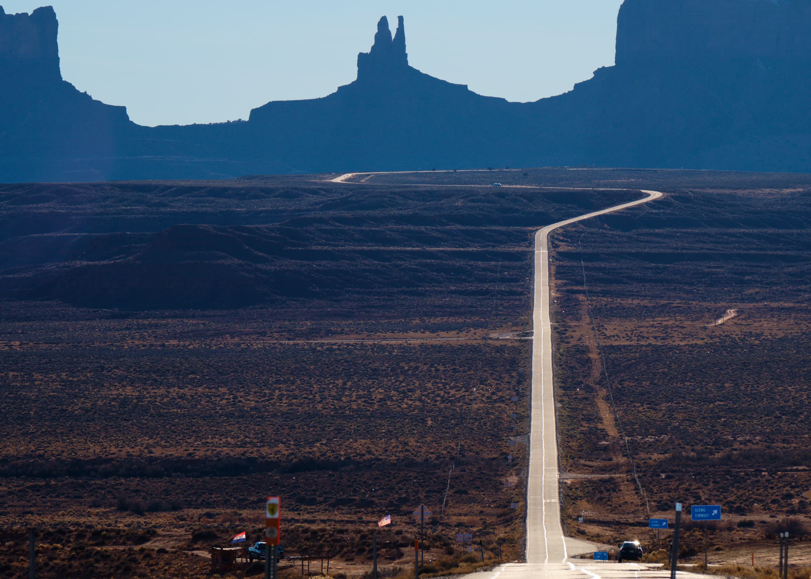 Long highway approaching Monument Valley buttes, telephoto