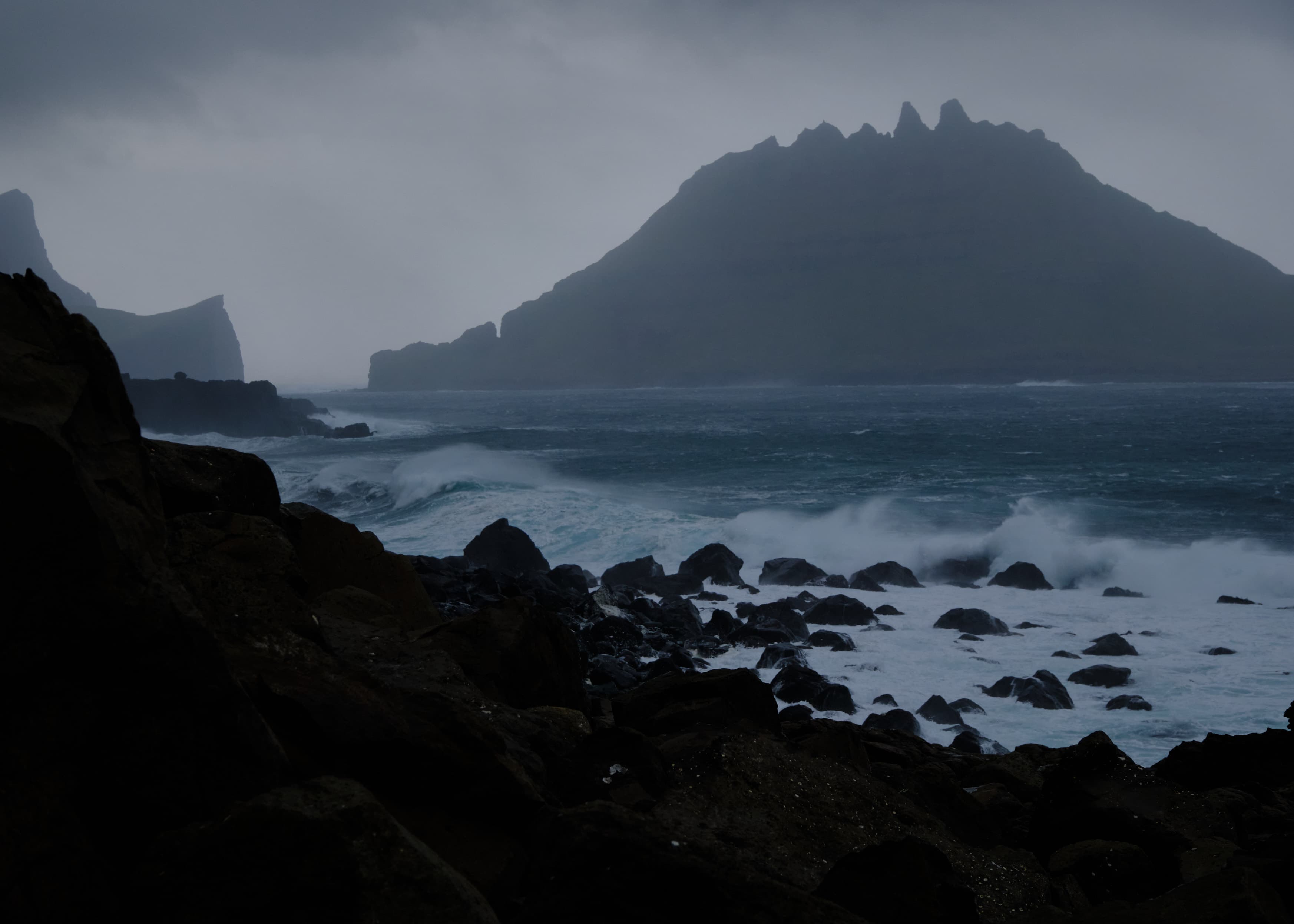 Dark rocky bay and jagged sea stacks in storm light