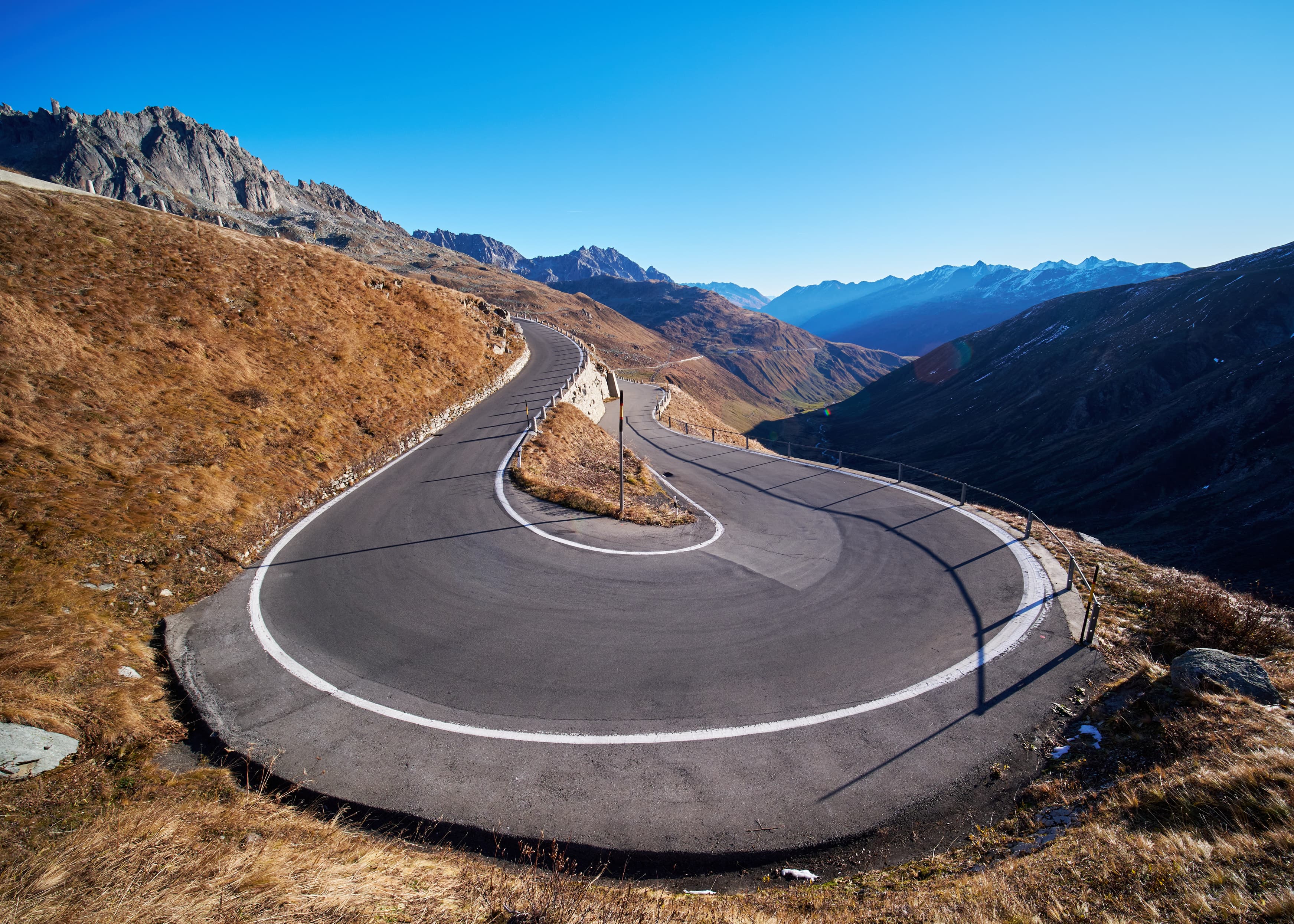Dramatic ultra-wide Sustenpass hairpin road, deep valley beyond
