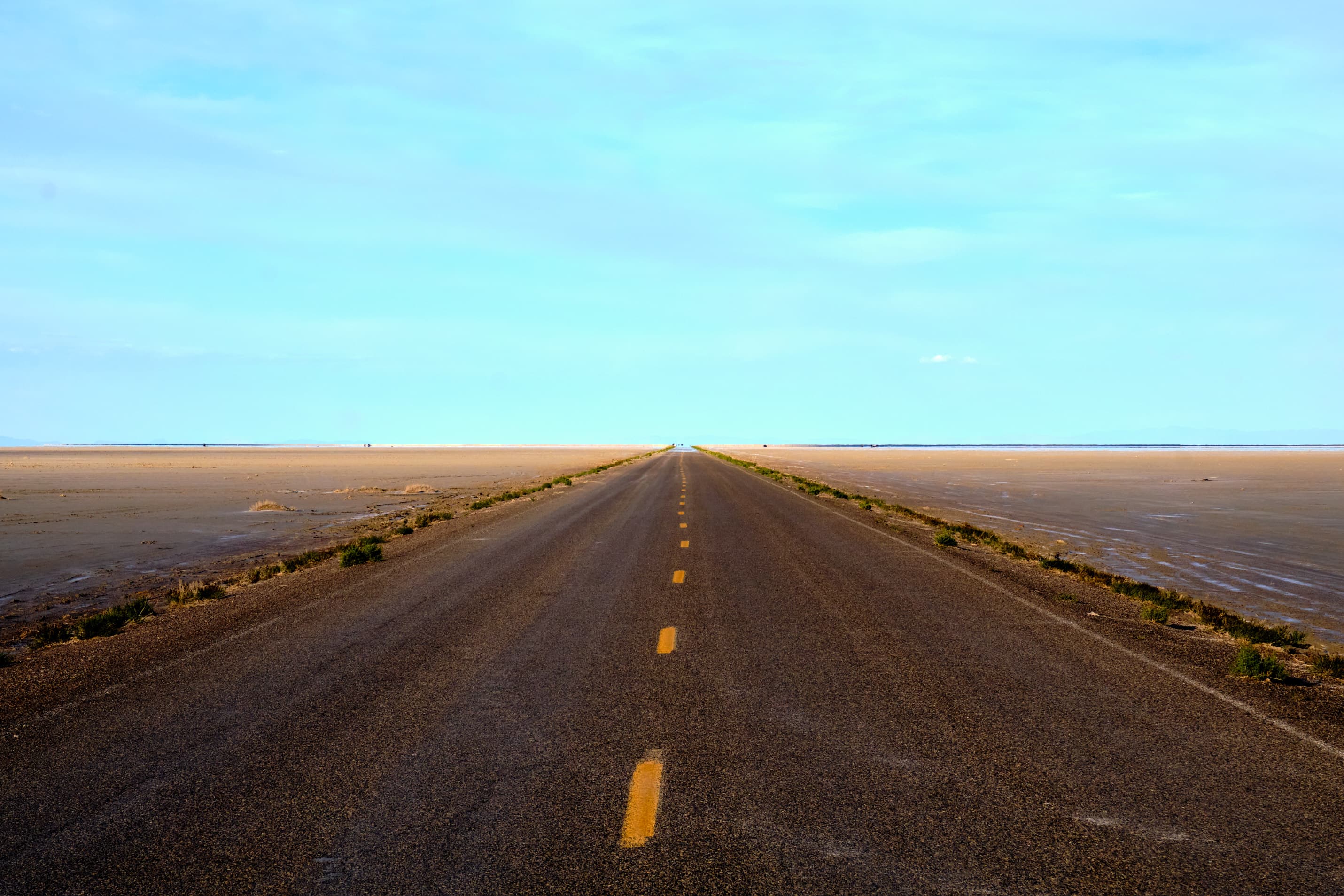 Perfectly straight highway across Nevada salt flat to horizon