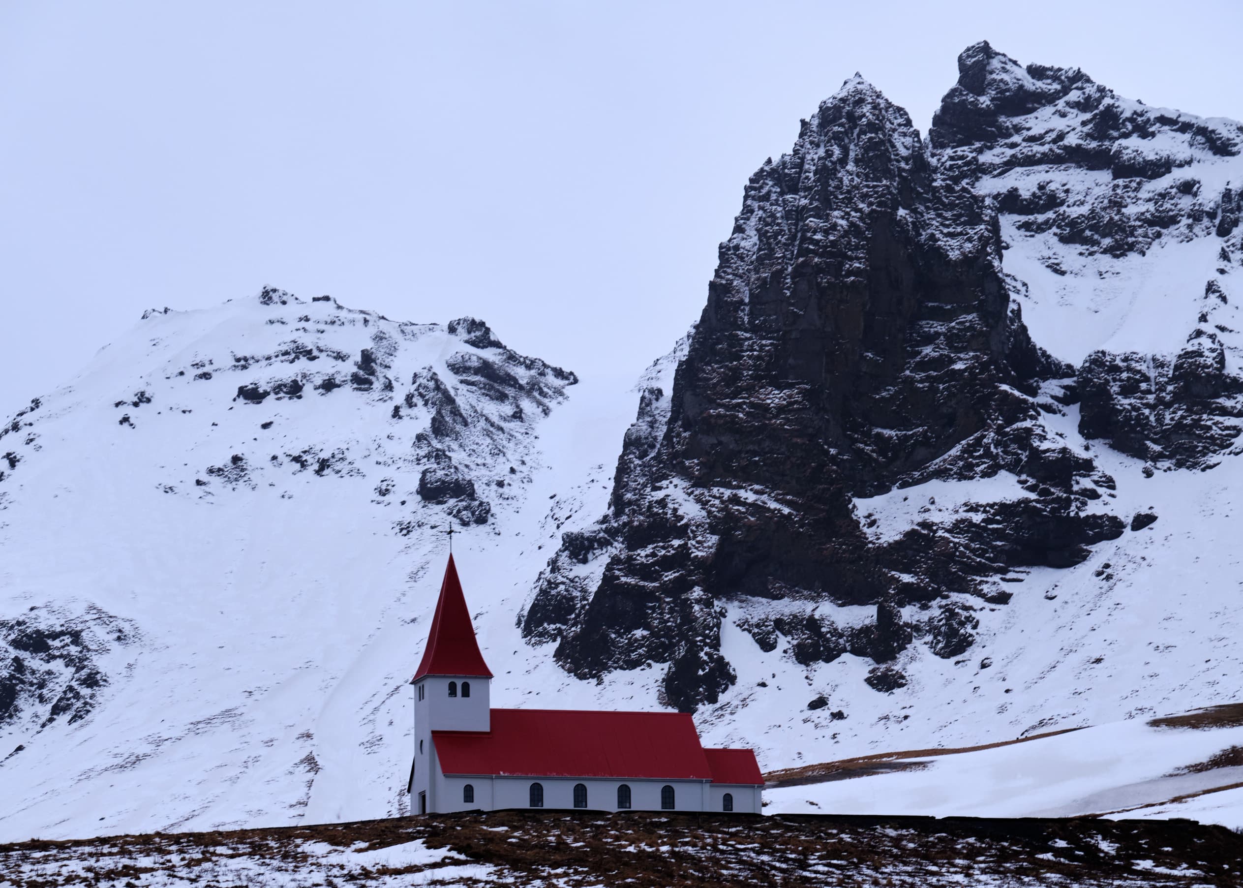 Iconic white church with red steeple in heavy snow