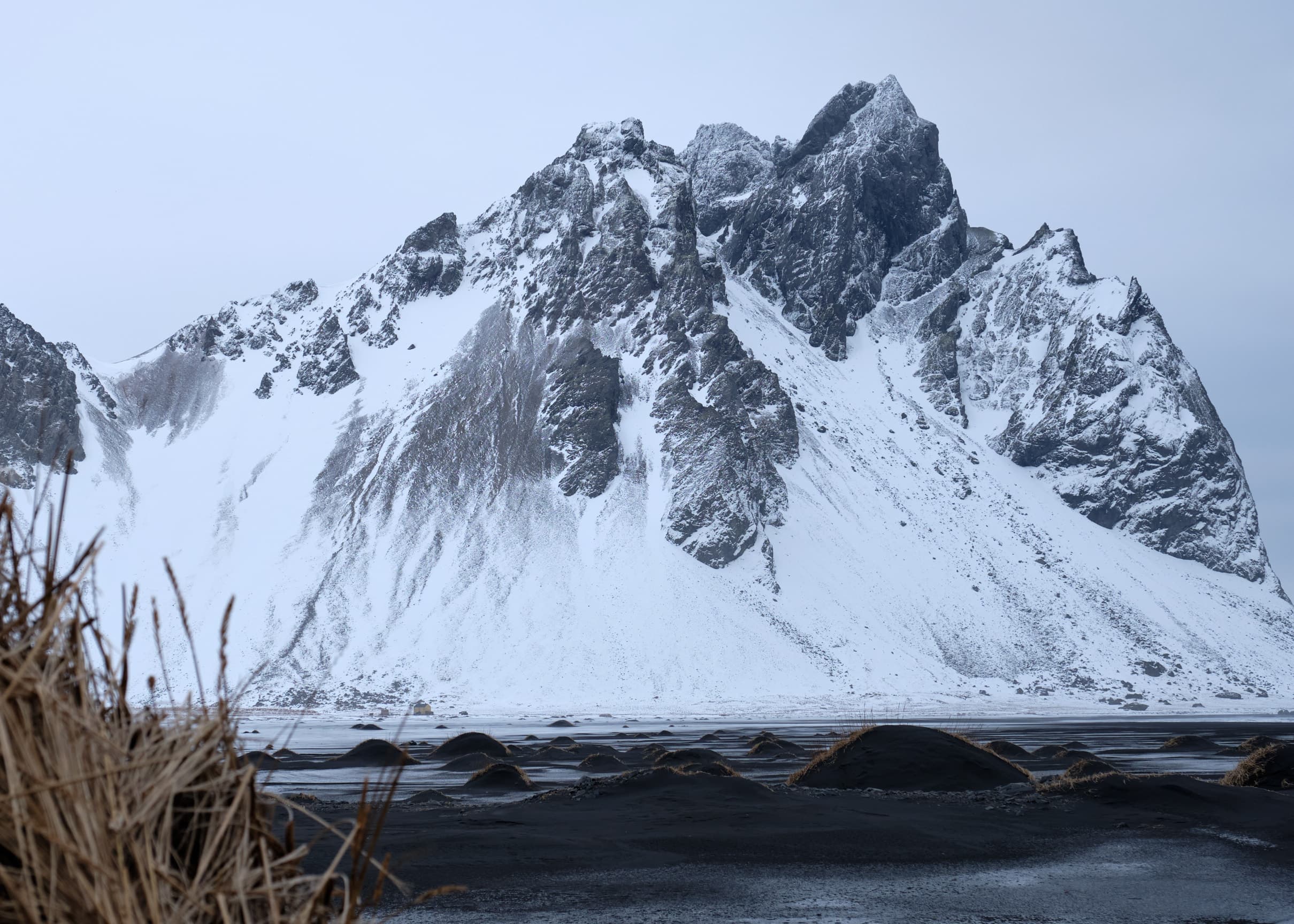 Vestrahorn over black sand dunes, figure in red
