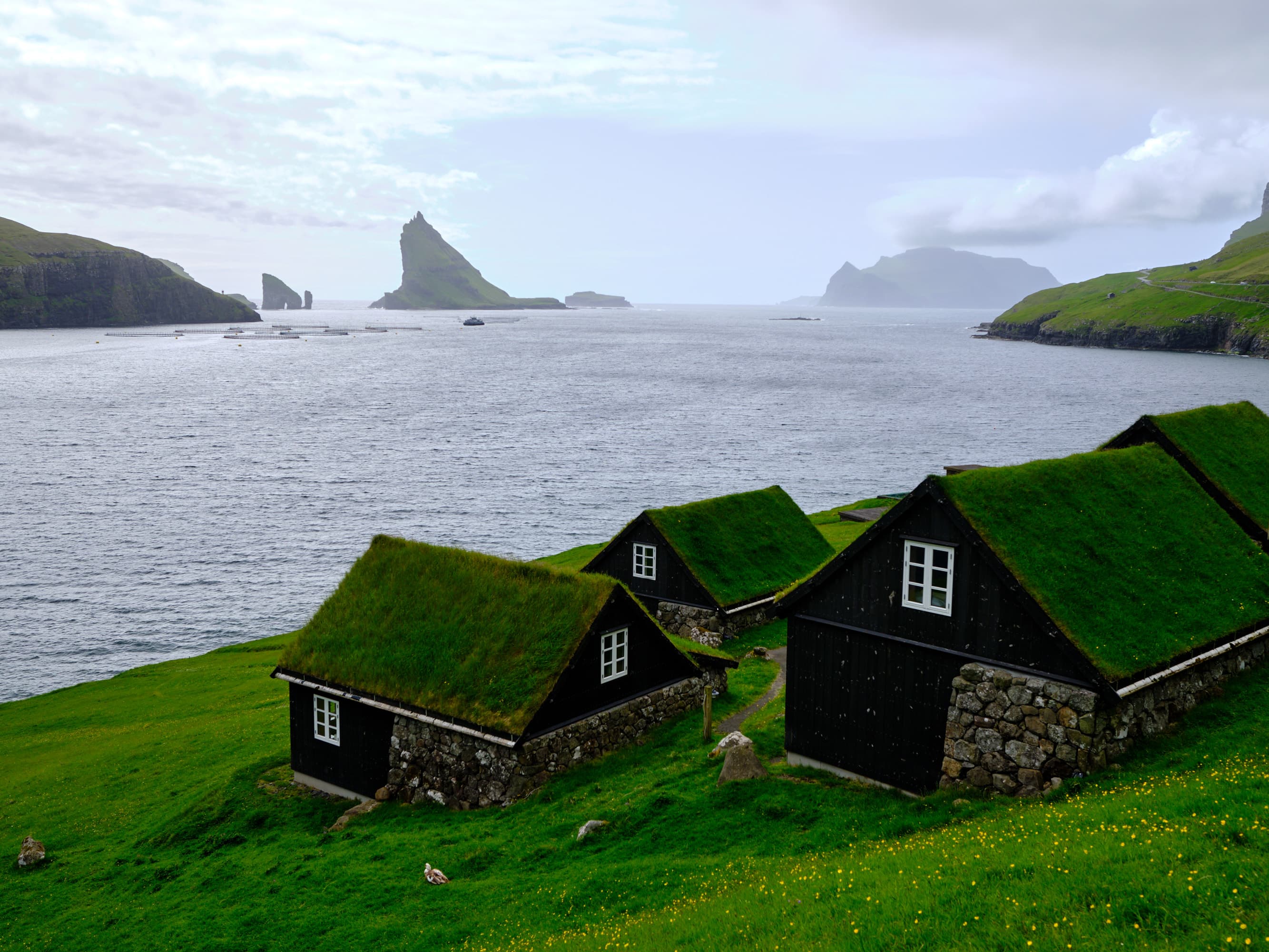 Turf-roofed cottages framed by Drangarnir sea stacks